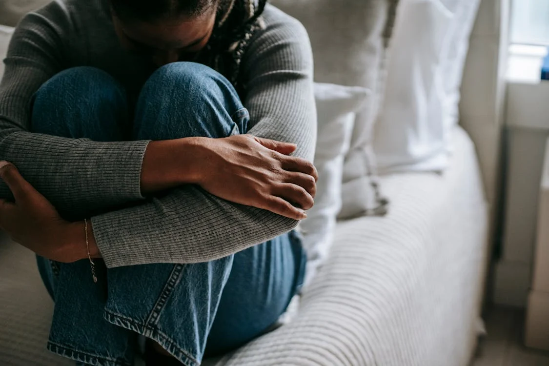 person sitting on bed in fetal position