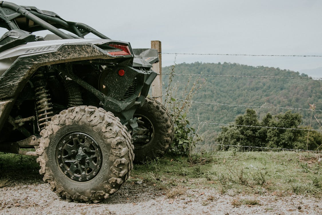 mud covered ATV parked next to wire fence overlooking valley