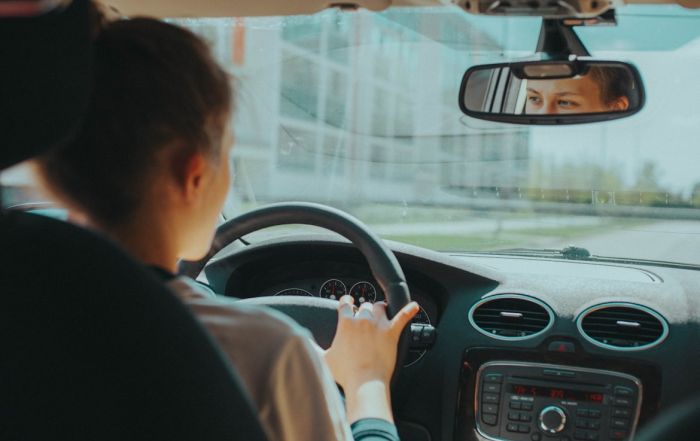 A picture taken from within a vehicle of a woman driving her car