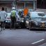 A police officer and civilian standing at the scene of two cars in a car accident