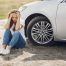 A woman looking upset, sitting outside of her car